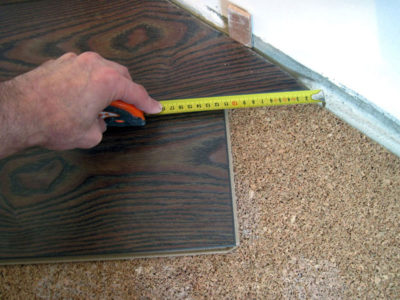 Sebelum memangkas tepi papan lamina, perlu mengukur jarak dari barisan lamina ke pasak jarak dengan tepat