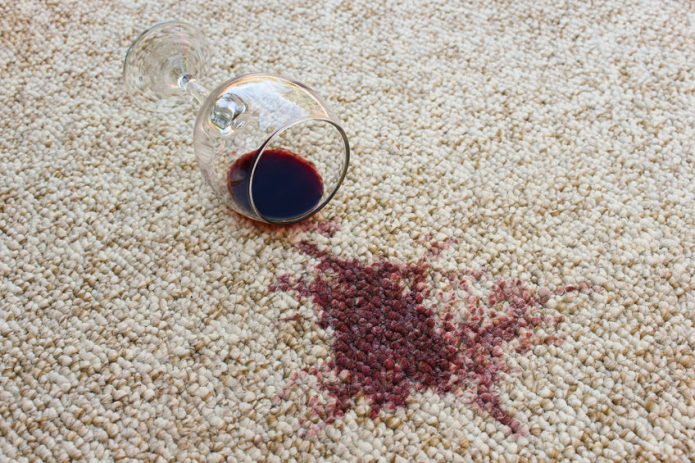 Stiklas ir išsiliejęs vynas ant kilimo