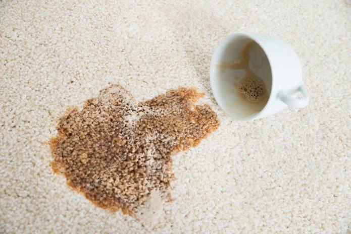 Taza y café derramado sobre la alfombra