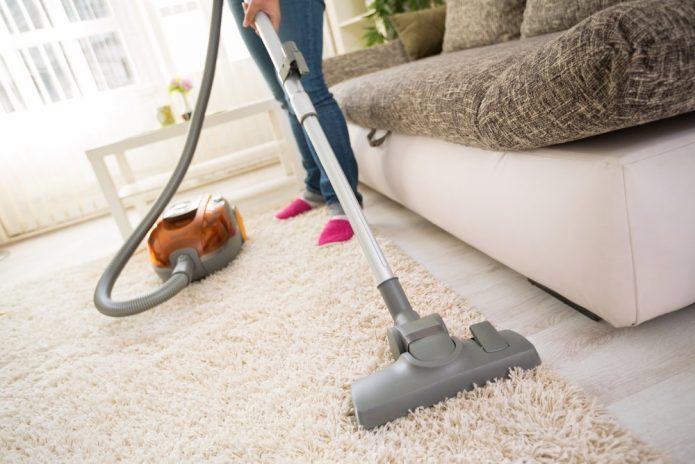Batang babae na vacuuming ang karpet