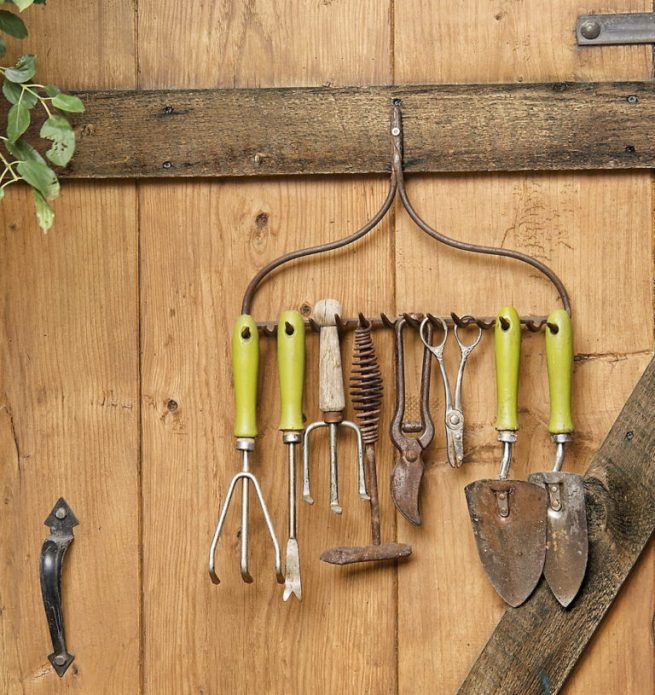 Percha original para herramientas de jardín en la puerta del granero.
