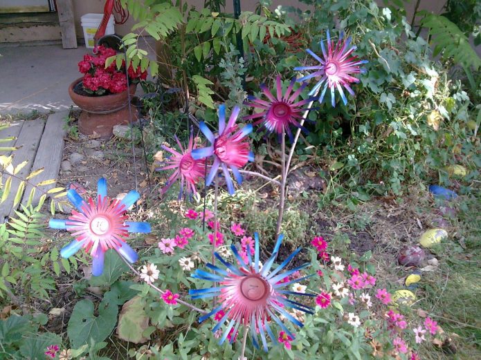 Lys håndværk fra dåser på en blomsterbed