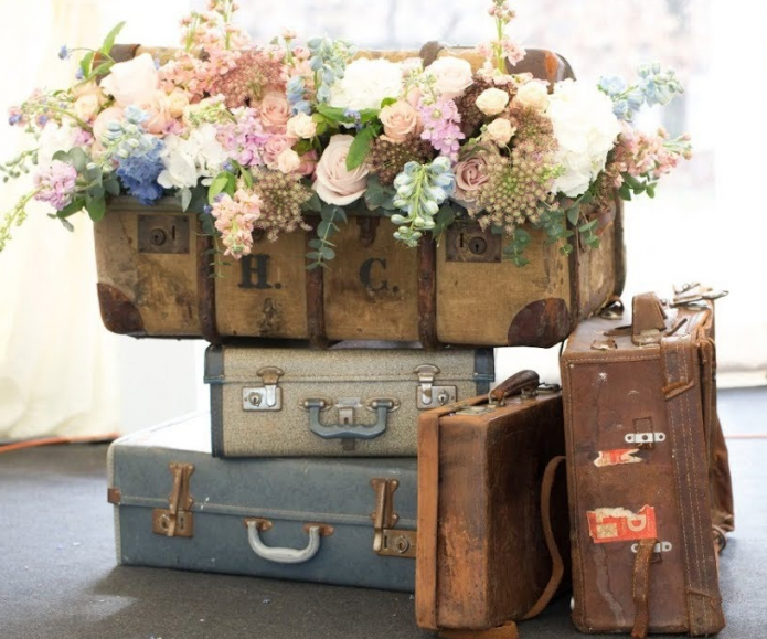 Sisustus kukista ja vanhoista matkalaukkuista